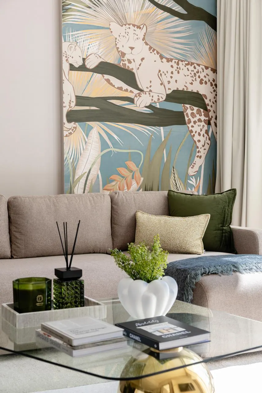 Living room with a leopard botanical wall panel, taupe sofa and glass coffee table