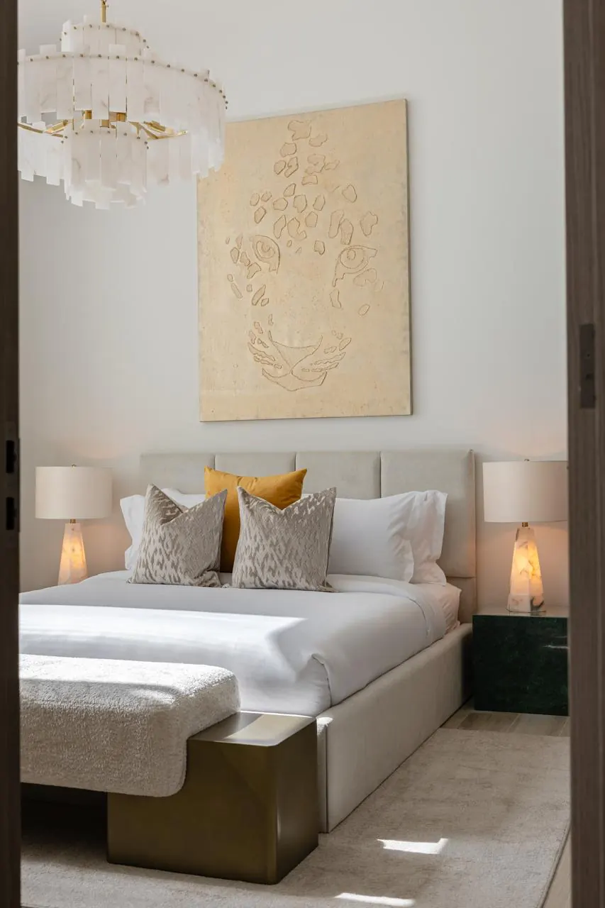 Bedroom with sculpted wall art, alabaster lamps and green marble bedside table