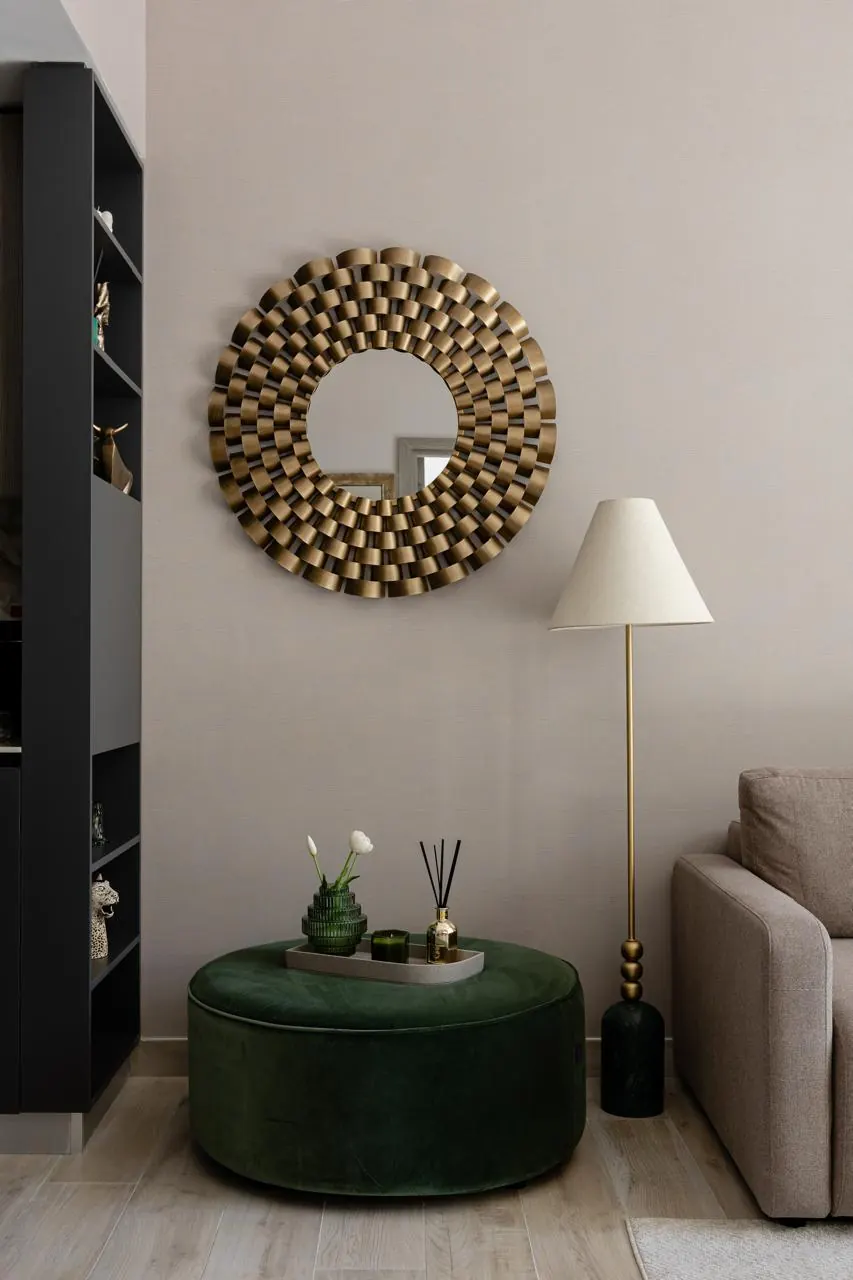 Reading corner with sunburst brass mirror, floor lamp and green velvet ottoman