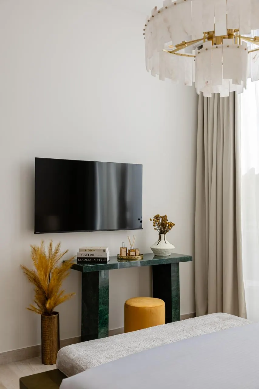 TV wall with green marble console and ochre pouf