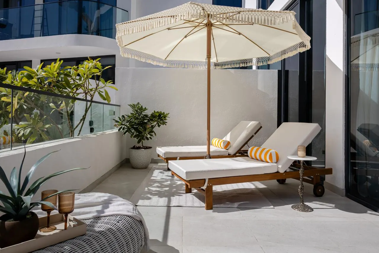 Terrace with timber loungers and fringed parasol